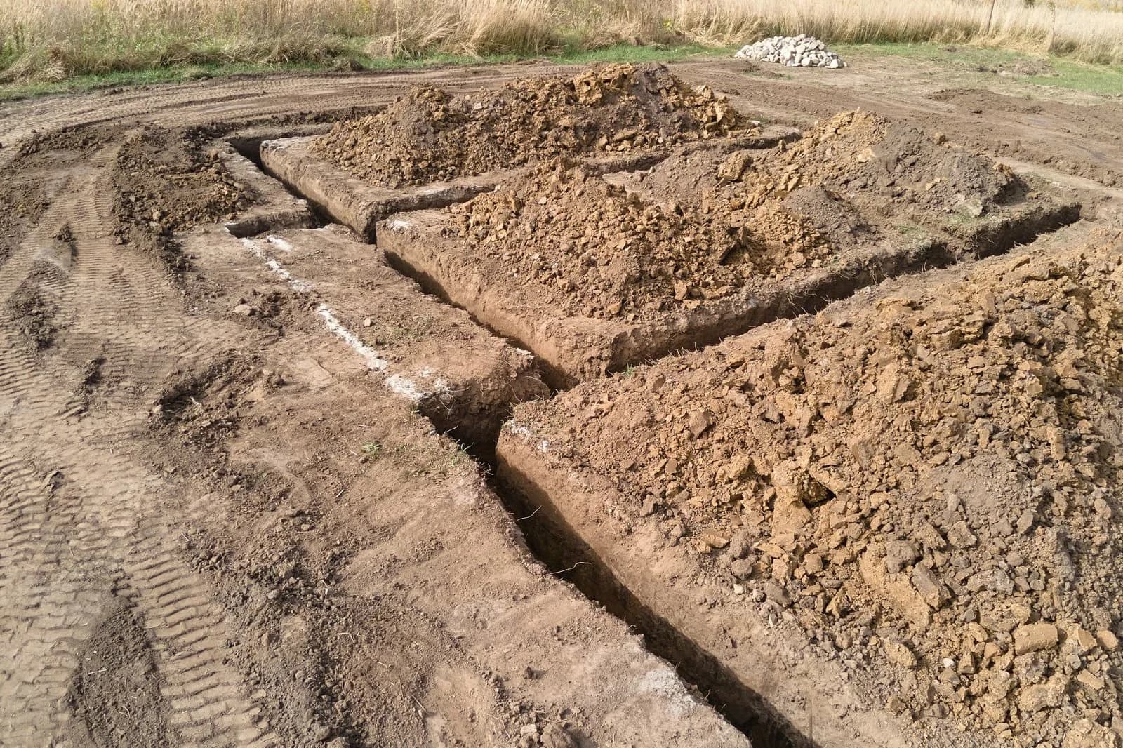 A commercial excavation site with open trenches and graded earth ready for utilities.